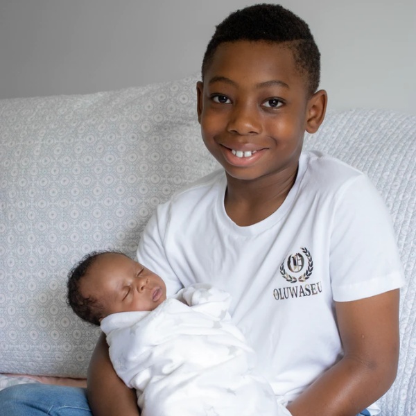 A young boy holding his newborn sibling